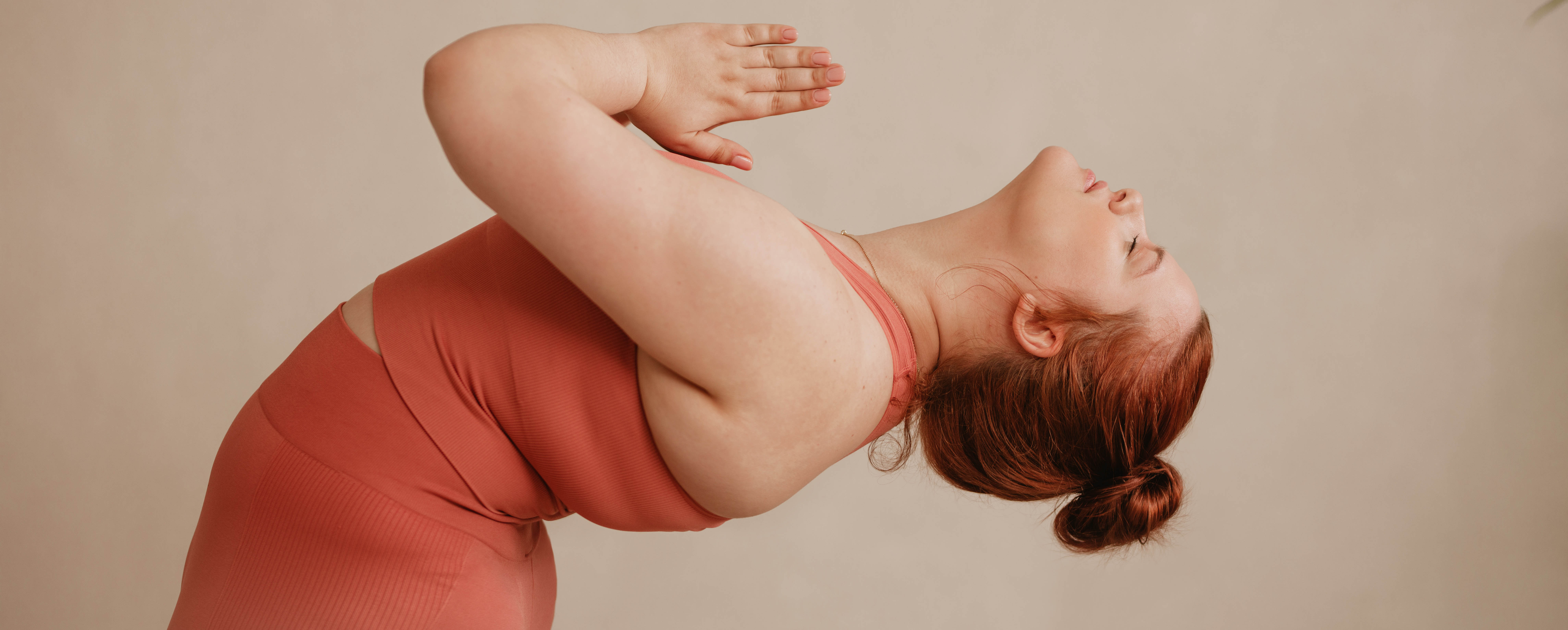 Woman doing a standing yoga backbend in an orange workout oufit